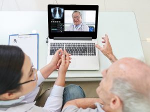Senior man and his doctor having video conference with experienced medical worker